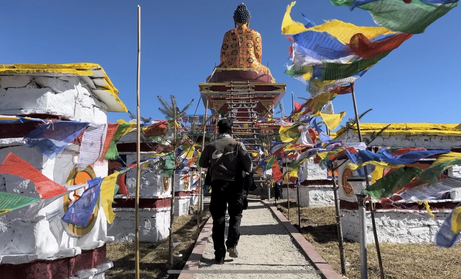 Walking towards a Buddha statue surrounded by prayer flags